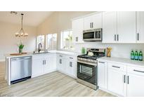 Bright kitchen features stainless steel appliances, white cabinets, and light wood flooring at 6124 Desert Haven Rd, Las Vegas, NV 89130