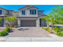 Charming two-story home with a brick driveway and landscaped front yard under a clear sky at 6442 Kobe Knoll Ct, Las Vegas, NV 89141