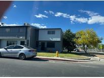 Two-story townhouse with gray siding, well-kept lawn, and mature trees against a blue sky at 816 E Nelson Ave # F, North Las Vegas, NV 89030