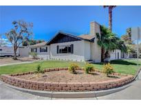 Charming single-story home featuring a well-manicured lawn, brick flower beds, and mature landscaping at 819 Bracken Ave, Las Vegas, NV 89104