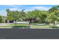 A well-maintained yard and mature trees frame this attractive home with a dark garage door at 9500 Balatta Canyon Ct, Las Vegas, NV 89144