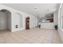 Spacious living room featuring tile flooring, arched doorways, and ample natural light from the large window at 2633 Chin Cactus Ct, Las Vegas, NV 89106