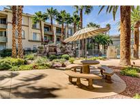 Community courtyard with picnic table, umbrella, rock waterfall, and lush desert landscaping by the pool at 7119 S Durango Dr # 303, Las Vegas, NV 89113