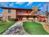 Two-story home with stone facade, red trim, a balcony, and well-manicured lawn at 7470 Eldora Av, Las Vegas, NV 89117