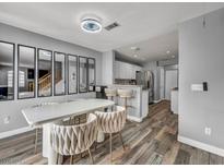 Bright dining area with modern table, chairs, and decorative mirrors, adjacent to the kitchen with wood floors at 5024 Starfinder Ave, Las Vegas, NV 89108