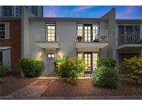 Inviting townhome featuring dual balconies, a brick pathway, blossoming shrubs, and exterior lighting at 530 Tam O Shanter, Las Vegas, NV 89109