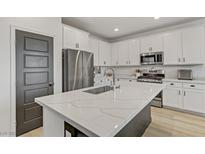 Modern kitchen featuring white cabinets, stainless steel appliances, and an island with a white countertop at 7122 Red Gulch St, North Las Vegas, NV 89084