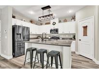 Modern kitchen boasts stainless steel appliances, granite counters, island with seating, and white cabinets at 10426 Mount Washington Ave, Las Vegas, NV 89166