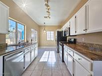 Bright kitchen features white cabinetry, tiled floors, stainless steel appliances, and ample counter space at 1851 Hillpointe Rd # 2124, Henderson, NV 89074