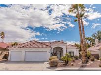 Charming single-story home with a three-car garage, tile roof, and lush landscaping under a bright blue sky at 2588 Mizzoni Cir, Henderson, NV 89052