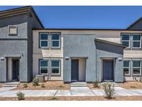 Modern two-story townhome with gray and beige stucco and well manicured landscaping at 6109 Aster Garden St # 159, North Las Vegas, NV 89081
