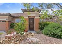 Inviting front entrance with a decorative door, desert landscaping, and covered porch at 7719 Villa Montara St, Las Vegas, NV 89123