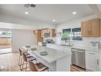 Bright kitchen features stainless steel appliances, white cabinets, quartz countertops, and an island with barstool seating at 40 Laswell St, Henderson, NV 89015