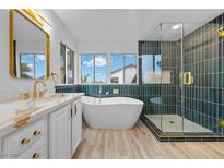 Elegant bathroom features a soaking tub, glass shower, and double vanity with gold hardware at 575 Dusty Palms Ln, Henderson, NV 89052