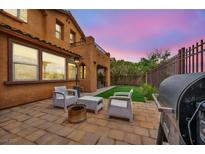 This cozy backyard has a barbecue, seating, and a patch of artificial grass at 617 Apricot Rose Pl, Las Vegas, NV 89138