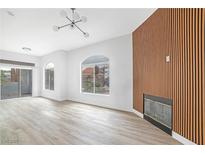 Bright living room with fireplace, wood accent wall, arched windows and sliding doors to the exterior patio at 700 Carnegie St # 3913, Henderson, NV 89052