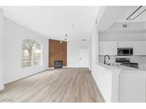 Bright living room featuring wood-look flooring, modern fireplace, and an open layout connected to the kitchen at 700 Carnegie St # 3913, Henderson, NV 89052