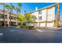 Condominium building with attached garages, beautiful landscaping, and palm trees, perfect for low-maintenance living at 7189 S Durango Dr # 203, Las Vegas, NV 89113
