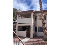 Two-story condo featuring stucco facade, small gated patio, and second-floor balcony in a well-maintained complex at 809 Rock Springs Dr # 202, Las Vegas, NV 89128