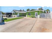 Charming green home featuring a spacious driveway and secured by a white horizontal slat fence at 4406 Parkchester Cir, Las Vegas, NV 89108
