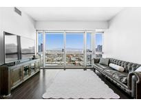 Bright living room features a leather sofa, sleek TV console, and expansive city views at 4471 Dean Martin Dr # 1502, Las Vegas, NV 89103