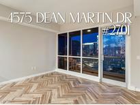 Bright living room boasts herringbone floors and expansive windows with city views at 4575 Dean Martin Dr # 2701, Las Vegas, NV 89103