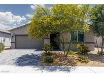 Charming single-story home showcasing lovely desert landscaping, a gray garage door, and a brick driveway at 5136 Stonecrop St, North Las Vegas, NV 89031