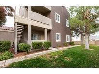 Neutral colored two-story home with a balcony, trimmed bushes, and a well-manicured lawn at 5250 S Rainbow Blvd # 1084, Las Vegas, NV 89118