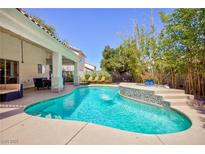 Inviting backyard pool with a waterfall feature and lounge chairs under the covered patio, surrounded by lush landscaping at 1246 E Gary Ave, Las Vegas, NV 89123