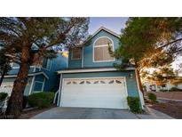 Charming two-story home with a white garage door and light blue exterior with mature landscaping at 3217 Symphony Dr, Las Vegas, NV 89146