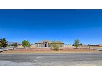 Expansive single-story home showcasing desert landscaping, circular driveway, and a symmetrical facade under a clear blue sky at 3780 Shawnee Ave, Pahrump, NV 89048