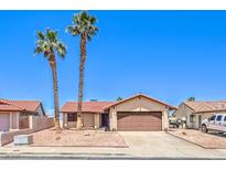 Charming single-story home featuring a two-car garage, desert landscaping, and palm trees at 403 Woodridge Dr, Henderson, NV 89015