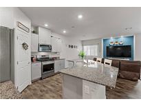 Modern kitchen featuring stainless steel appliances, white cabinetry, and granite countertops flowing to the living room at 4650 Ridgeley Ave # 103, North Las Vegas, NV 89084