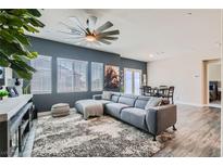 Bright living room featuring a plush gray sectional sofa, a modern ceiling fan, and stylish decor at 4720 Flower Moon Ave # 101, North Las Vegas, NV 89084