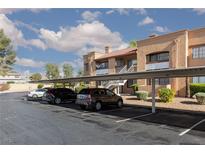 Exterior view of a two-story condo with covered parking and desert landscaping under a partly cloudy sky at 5114 S Jones Blvd # 202, Las Vegas, NV 89118
