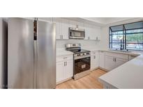 Modern kitchen featuring stainless steel appliances, white cabinetry, and a window overlooking the yard at 8412 Mulcahy Ave, Las Vegas, NV 89145