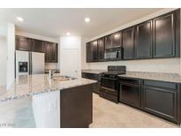 Modern kitchen features dark cabinets, stainless steel appliances, and a large island with granite countertops at 2824 Mozia Ct, Henderson, NV 89044
