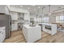 Modern white kitchen featuring stainless steel appliances, center islands, and wood-look flooring at 1964 Oliver Springs St, Henderson, NV 89052