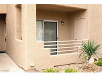 Exterior view of a condo with a private patio, tan stucco walls, and a small potted plant at 2191 Bay Club Dr # 102, Laughlin, NV 89029