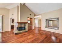 Spacious living room featuring a cozy fireplace, high ceilings, and rich hardwood flooring at 2832 Cape Hope Way, Las Vegas, NV 89121