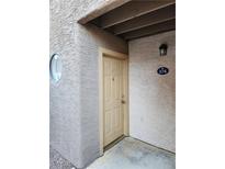Exterior view of a well-kept condo featuring a beige door and round window near the entrance at 2974 Juniper Hills Blvd # 104, Las Vegas, NV 89142