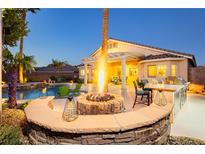 Stunning backyard featuring a fire pit, outdoor kitchen, pool, and covered patio for ultimate relaxation at 10243 Cowboys Dream St, Las Vegas, NV 89131