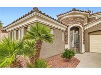 Charming home entrance featuring an ornate gate, stone accents, and desert landscaping at 11278 Tenza Ct, Las Vegas, NV 89141