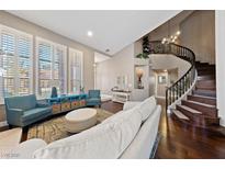 Bright living room featuring a curved staircase, large windows with shutters, and neutral decor at 2113 Waterbury Ln, Las Vegas, NV 89134