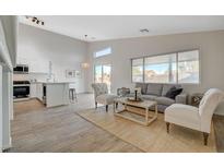 Bright living room featuring neutral tones, wood-look flooring, and an open concept design flowing into the kitchen at 4331 Golden Palomino Ln, North Las Vegas, NV 89032