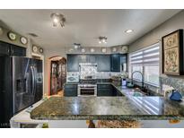 Updated kitchen featuring granite counters, stainless steel appliances, stylish backsplash, and painted cabinets at 4735 Roby Grey Way, North Las Vegas, NV 89081