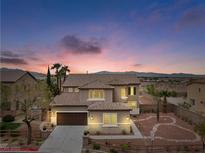 Charming two-story home with stone accents and a well-manicured front yard at dusk at 7756 River Mist Ct, Las Vegas, NV 89113
