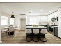 Bright kitchen with white cabinets, gray island with seating, stainless steel appliances, and wood-look floors at 8757 Beluga Way, Las Vegas, NV 89117