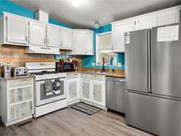 Well-lit kitchen featuring white cabinetry, stainless steel appliances, and a neutral-toned backsplash at 240 Navajo Dr, Henderson, NV 89015