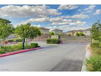 Community entrance with landscaped median, gate, and multi-story homes under a partly cloudy sky at 7052 Blissful Peak St, North Las Vegas, NV 89084